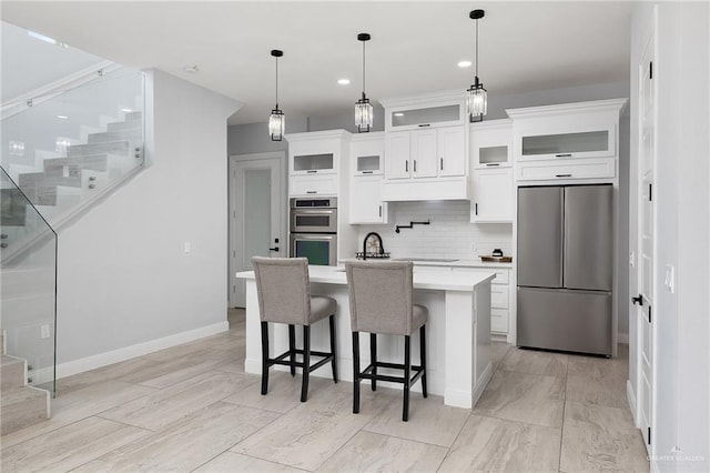 3306 Lauren Dr, Palmview, TX 78574 - kitchen with a kitchen bar, an island with sink, backsplash, light countertops, and appliances with stainless steel finishes