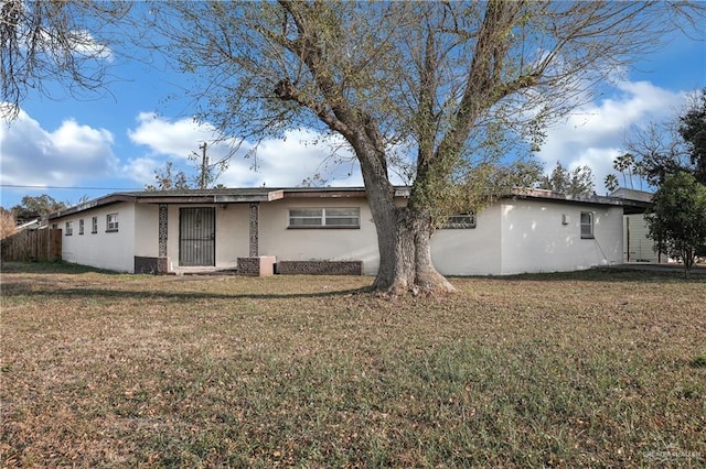 rear view of property with stucco siding, central AC, a yard, and fence