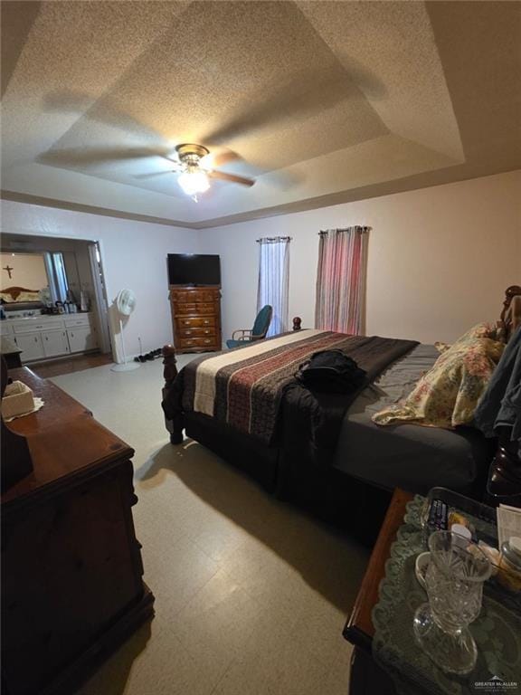 bedroom featuring a tray ceiling, tile patterned floors, a ceiling fan, and a textured ceiling