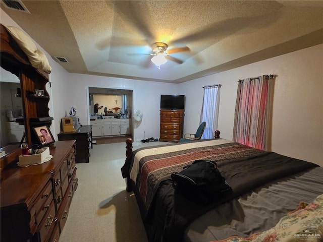 carpeted bedroom featuring a tray ceiling, a textured ceiling, a ceiling fan, and visible vents