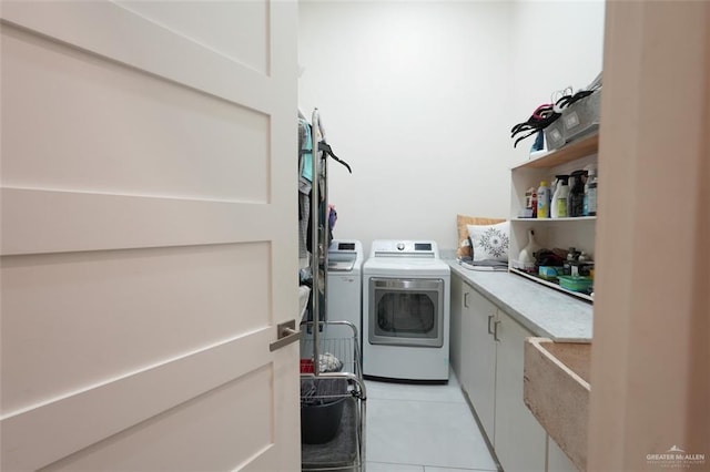 clothes washing area featuring light tile patterned floors, cabinet space, and separate washer and dryer