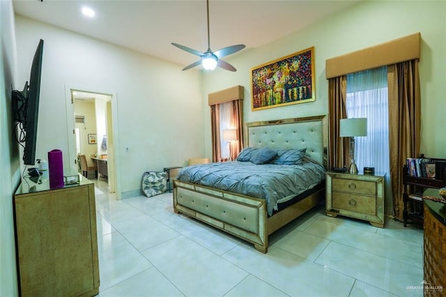 bedroom with a ceiling fan, light tile patterned flooring, and connected bathroom