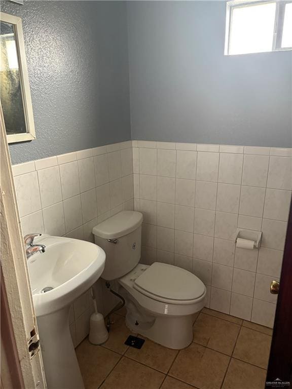 bathroom with tile walls, tile patterned floors, and toilet