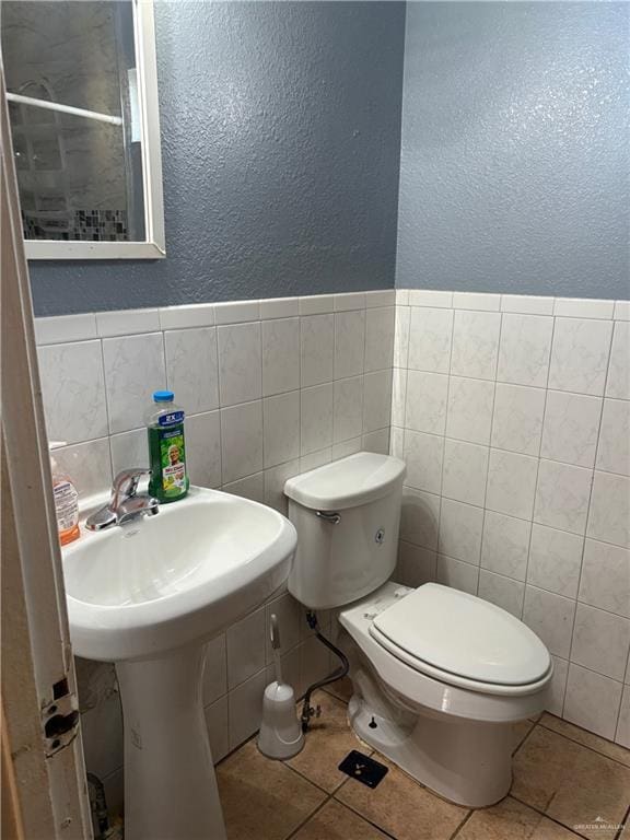 bathroom featuring tile walls, tile patterned flooring, and toilet