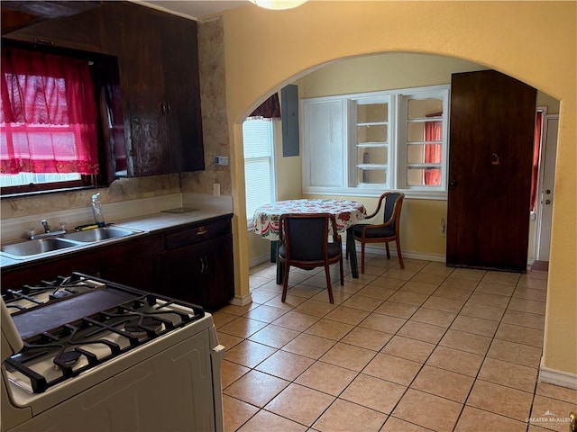 kitchen with light tile patterned floors, sink, electric panel, and white gas range oven