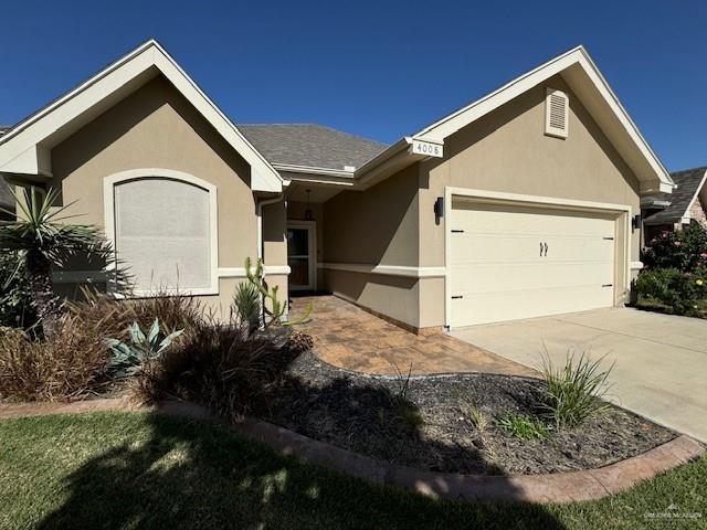 ranch-style house featuring an attached garage, concrete driveway, and stucco siding