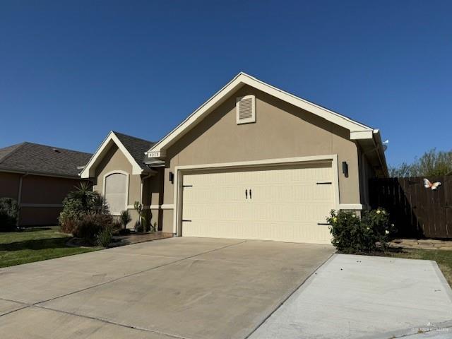 ranch-style home featuring concrete driveway, an attached garage, fence, and stucco siding