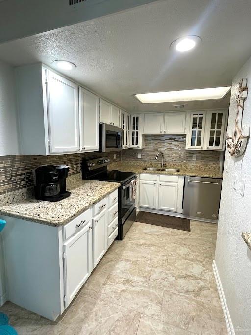 kitchen with white cabinets, decorative backsplash, sink, and stainless steel appliances