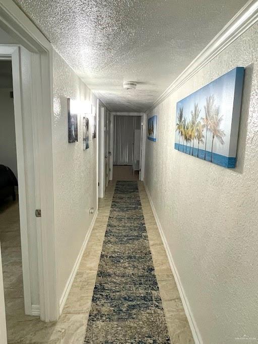 hall featuring a textured ceiling and ornamental molding