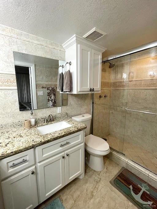 bathroom featuring toilet, vanity, a textured ceiling, and walk in shower