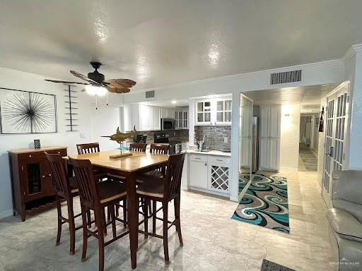 dining area with ceiling fan and ornamental molding