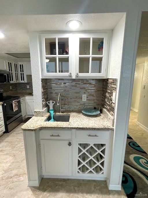 kitchen featuring backsplash, stainless steel appliances, white cabinetry, and sink