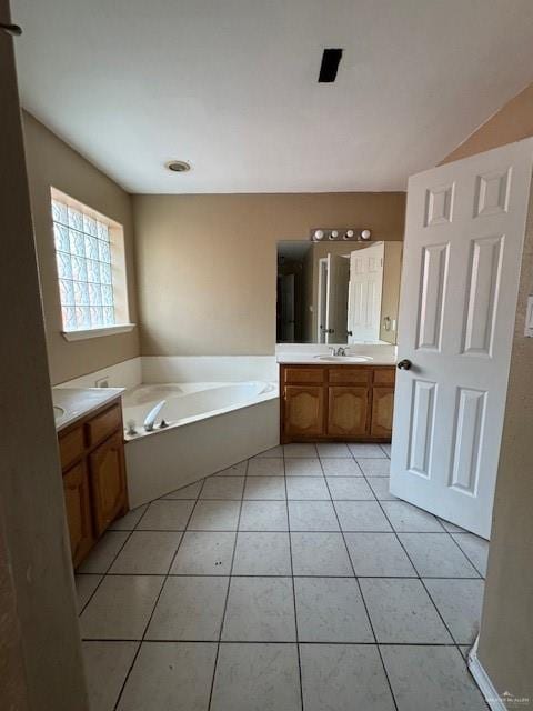 bathroom with tile patterned floors, a washtub, and vanity