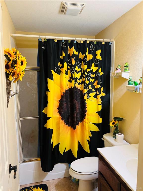 full bathroom featuring toilet, vanity, tile patterned floors, and shower / bath combo with shower curtain