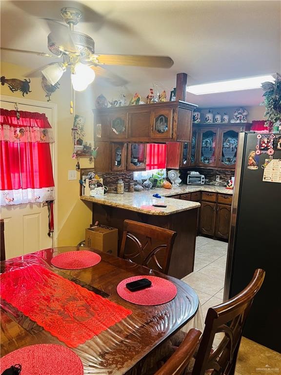 kitchen featuring stainless steel fridge, light tile patterned floors, dark brown cabinets, and ceiling fan