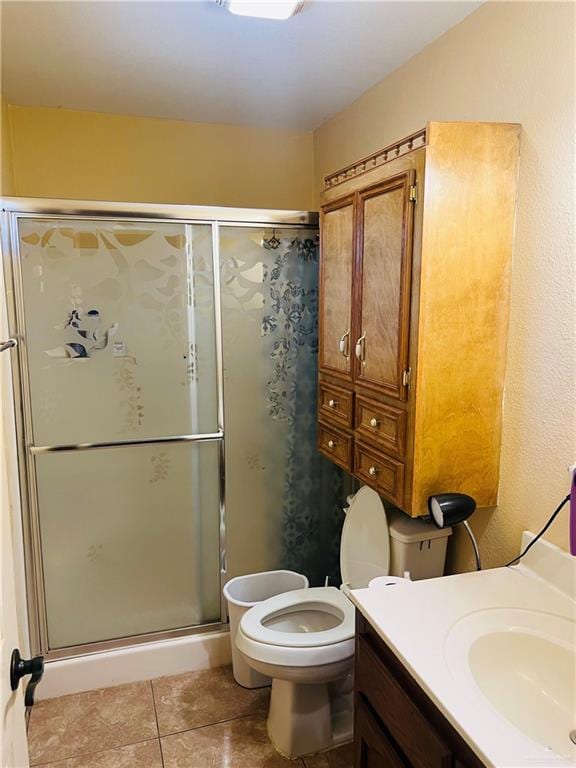 bathroom with tile patterned floors, vanity, toilet, and a shower with door