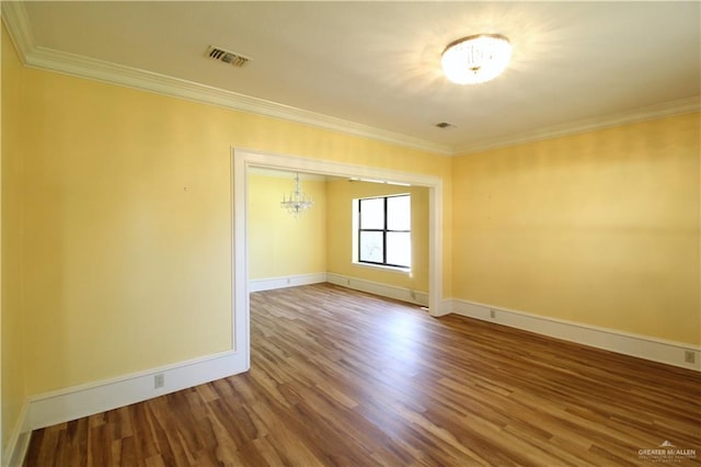 empty room with hardwood / wood-style floors, an inviting chandelier, and ornamental molding