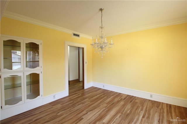 unfurnished dining area featuring hardwood / wood-style flooring, an inviting chandelier, and ornamental molding