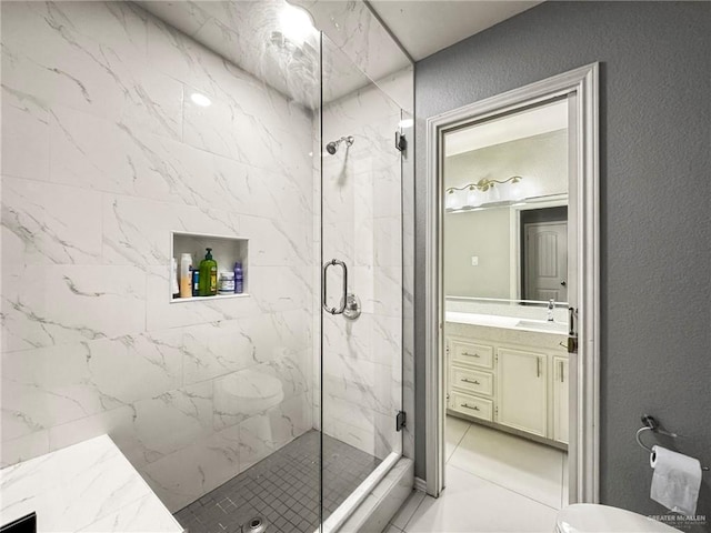 bathroom with a shower with door, vanity, and tile patterned flooring