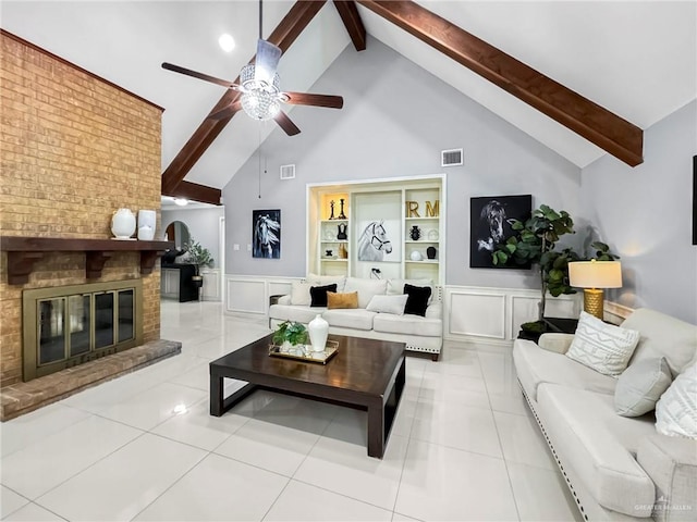 tiled living room with ceiling fan, high vaulted ceiling, built in features, beamed ceiling, and a fireplace