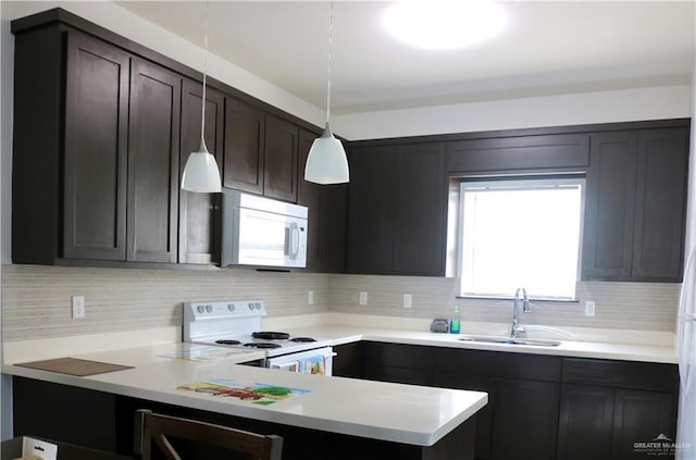 kitchen featuring a wealth of natural light, pendant lighting, sink, backsplash, and white appliances