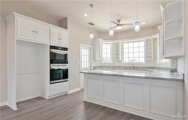 27406 S Kelly Ct, La Feria, TX 78559 - kitchen featuring stainless steel double oven, white cabinets, open shelves, decorative backsplash, and light stone countertops
