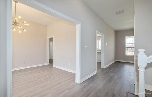 unfurnished living room featuring light wood-type flooring and a notable chandelier