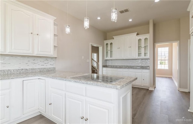 kitchen with white cabinets, decorative light fixtures, kitchen peninsula, and backsplash