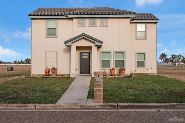 view of front of house featuring a tile roof, a front lawn, and stucco siding