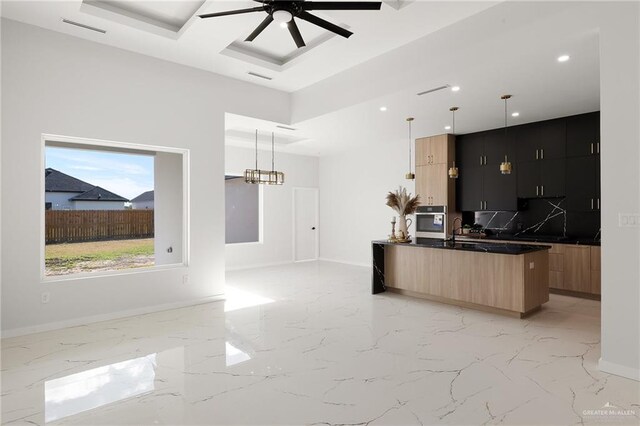 kitchen featuring backsplash, light brown cabinetry, oven, and hanging light fixtures