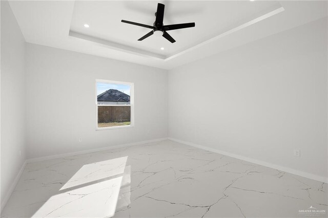 empty room featuring a raised ceiling and ceiling fan