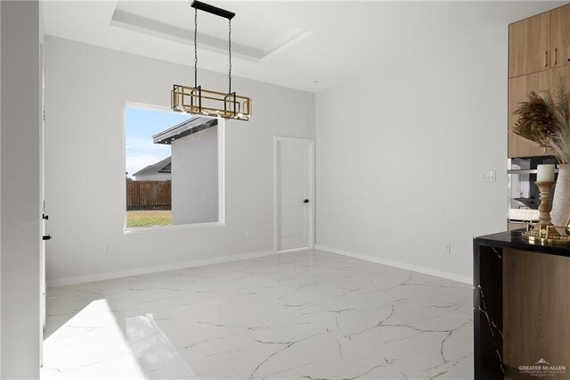 unfurnished dining area featuring a tray ceiling