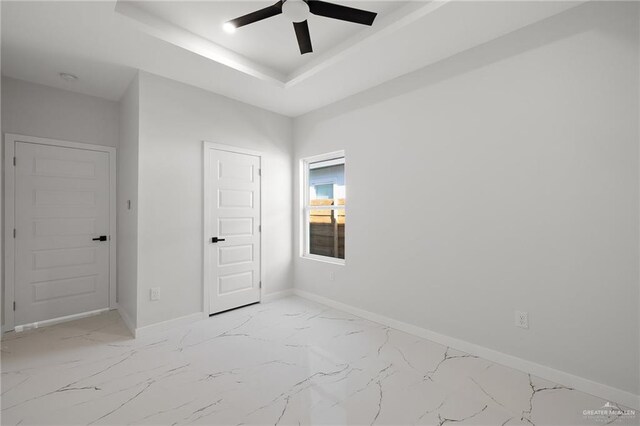 interior space with a tray ceiling, ceiling fan, and a closet