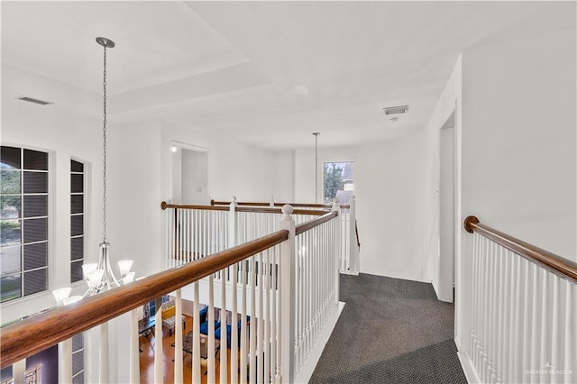 hall with a chandelier and dark carpet