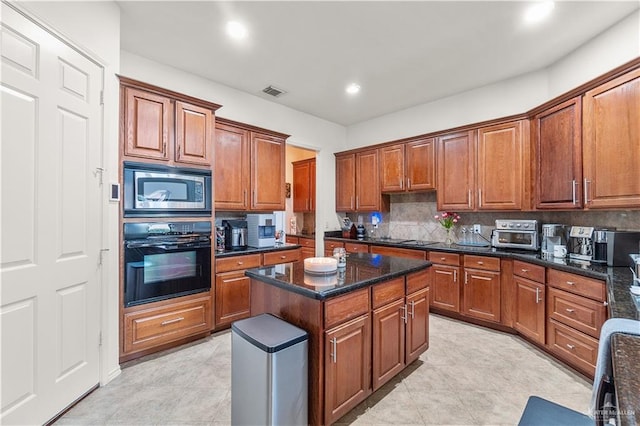 kitchen with tasteful backsplash, dark stone counters, black appliances, light tile patterned floors, and a center island