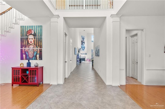 hall with light wood-type flooring and decorative columns