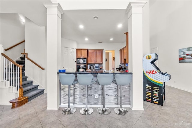 kitchen with oven, stainless steel microwave, kitchen peninsula, and a breakfast bar area