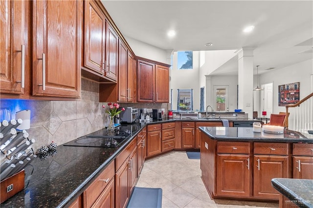 kitchen featuring backsplash, black electric cooktop, sink, dark stone countertops, and light tile patterned flooring