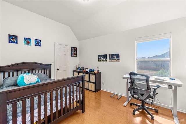 bedroom featuring a mountain view, wood-type flooring, and vaulted ceiling