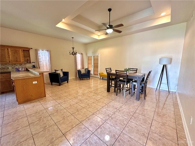 dining area featuring ceiling fan with notable chandelier, a raised ceiling, and light tile patterned flooring