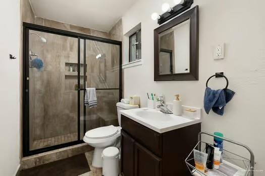 bathroom with vanity, a shower with shower door, and toilet