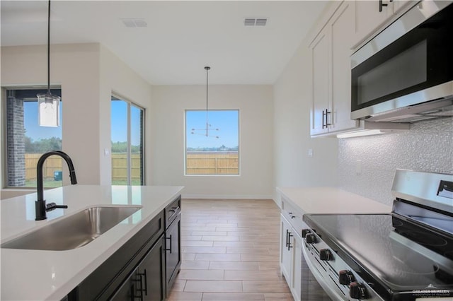 kitchen featuring appliances with stainless steel finishes, decorative light fixtures, sink, and white cabinets