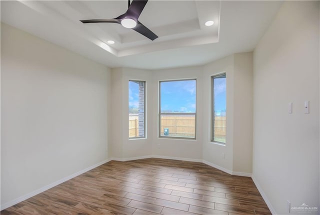 empty room featuring hardwood / wood-style floors, a tray ceiling, and ceiling fan