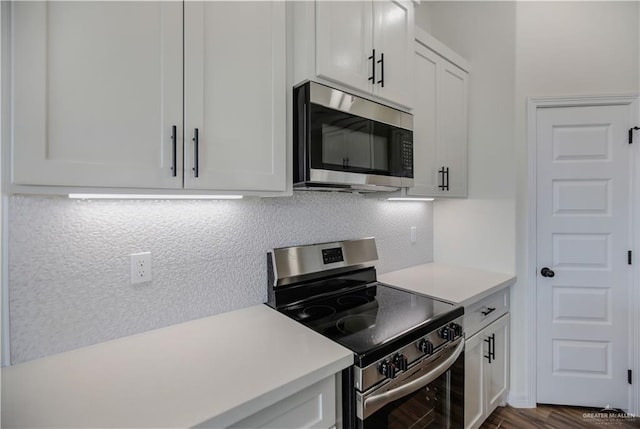 kitchen with tasteful backsplash, stainless steel appliances, dark wood-type flooring, and white cabinets