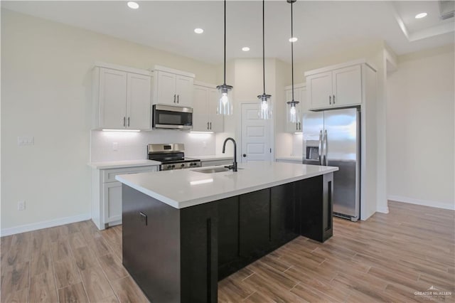 kitchen with appliances with stainless steel finishes, sink, a center island with sink, and white cabinets