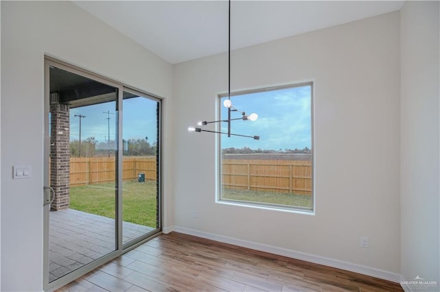 unfurnished dining area featuring wood-type flooring and a chandelier