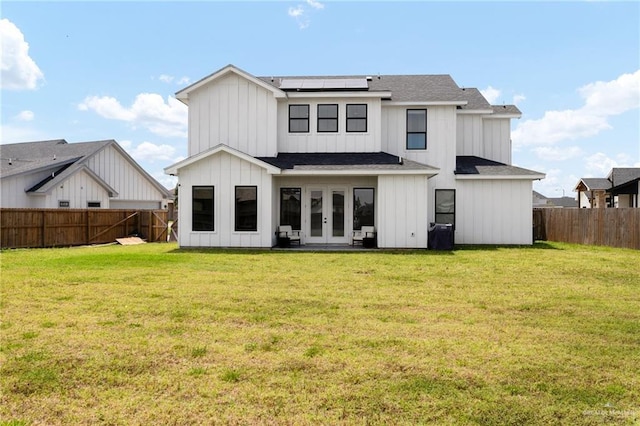 1405 Jocelyn Cir, Harlingen, TX 78552 - back of property featuring board and batten siding, solar panels, a yard, french doors, and a fenced backyard
