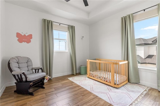 1405 Jocelyn Cir, Harlingen, TX 78552 - bedroom featuring ceiling fan, a tray ceiling, baseboards, a crib, and wood finished floors