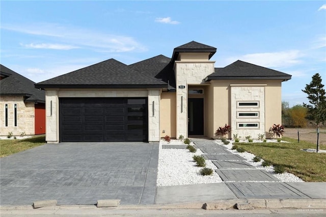 prairie-style home featuring stucco siding, an attached garage, decorative driveway, and a shingled roof