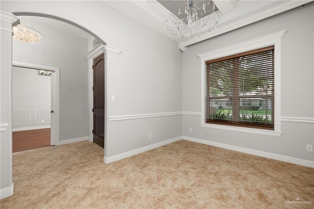 empty room featuring ornate columns and an inviting chandelier